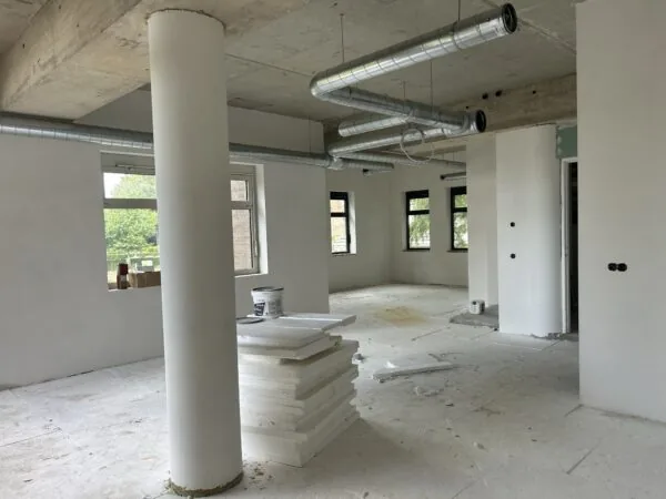 Binnenruimte in verbouwing aan de Bergse Dorpsstraat met zichtbare isolatieplaten, ventilatiebuizen en onafgewerkte muren.